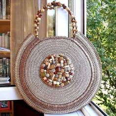 a woven purse sitting on top of a window sill next to a book shelf