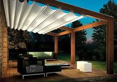 an outdoor living area with couches and tables under a pergolated awning