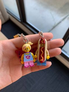 a person holding two legos in their hand, one with a hot dog and the other with a bun