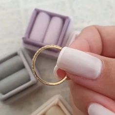 a woman's hand holding a ring in front of some jewelry boxes