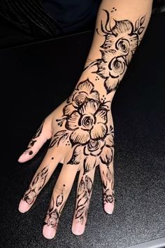 a woman's hand with black ink and flowers on the palm, which is decorated with