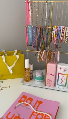 a table topped with lots of jewelry and personal care items next to a yellow box