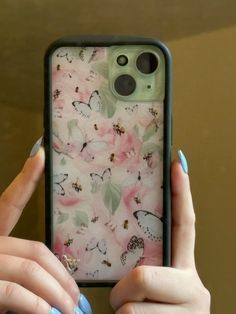 a woman holding up her phone case with butterflies on it