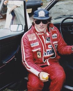 a man sitting in the driver's seat of a car holding an apple and wearing sunglasses