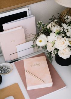 a desk with flowers and notebooks on it