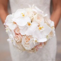 a bride holding a bouquet of white and pink flowers