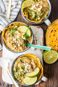 three bowls filled with chicken tortilla soup and topped with cilantro, lime wedges