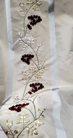 an embroidered white and red floral design on a satin material with gold trimmings