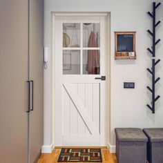 an entryway with a bench, coat rack and storage area on the side wall