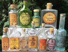 an assortment of liquor bottles sitting on top of a wooden table in front of trees