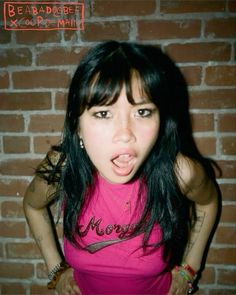 a young woman making a funny face in front of a brick wall