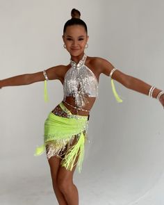 a young woman in a lime green and silver outfit dancing with her arms out to the side