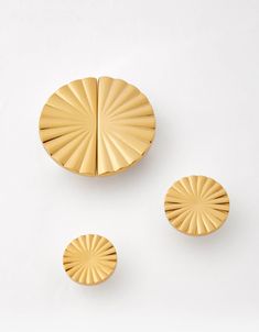 three gold colored objects on a white surface, including one round and the other circular