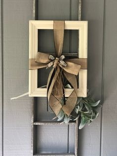 an old ladder is decorated with burlock and a bow for the front door