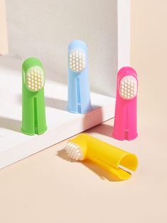 three different colored toothbrushes sitting next to each other on a white counter top