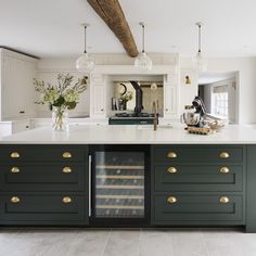 a large kitchen with green cabinets and white counter tops, an island in the middle