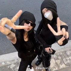 two women wearing masks and pointing fingers at the camera