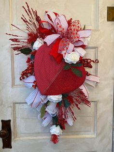 a heart shaped wreath with flowers and ribbons on the front door for valentine's day