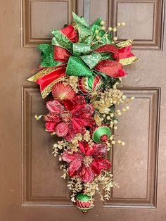 a red and green christmas wreath hanging on a door