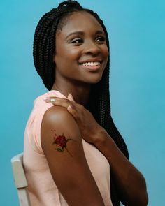 a woman with a rose tattoo on her arm, smiling and looking at the camera