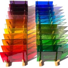 several colorful pieces of glass stacked on top of each other with wooden pegs in front of them