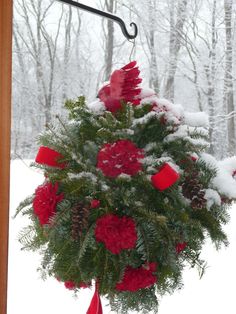 a christmas wreath hanging from a window in the snow