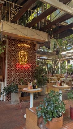 the inside of a restaurant with tables and potted plants on the outside patio area