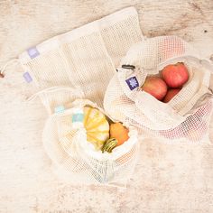 two bags filled with fruit sitting on top of a wooden table