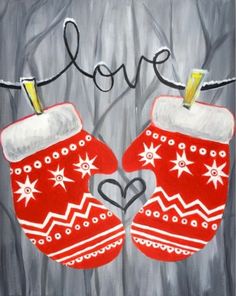 two red mittens hanging from a clothes line with the word love painted on it