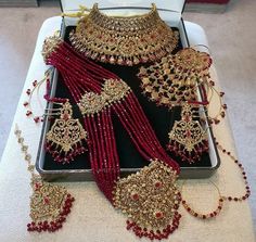 an assortment of red and gold necklaces on display in a jewelry box with white carpet