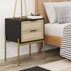 a nightstand with two drawers and a lamp on top of it next to a bed