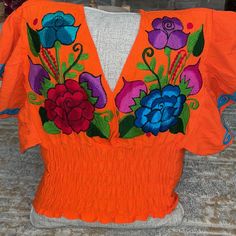 Cute Orange Top With A Beautiful Flower Blue Hot Pink Purple And Red Beautiful Work Elastic From The Waist Open V-Neck Front And Back Never Been Worn Colorful Cotton V-neck Tops, Orange V-neck Top For Festivals, Colorful Short Sleeve Festival Tops, Colorful Short Sleeve Tops For Festival, Orange Cotton Festival Top, Vibrant Multicolor Tops For Festivals, Vibrant Orange Fitted Top, Vibrant Orange V-neck Top, Vibrant Red V-neck Top