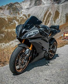 a black motorcycle parked on the side of a road next to a mountain covered in snow