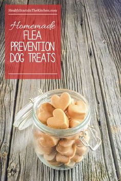 a jar filled with heart shaped dog treats on top of a wooden table next to a red sign that says homemade flea prevention dog treats