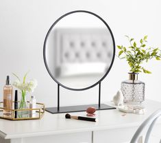 a mirror sitting on top of a table next to a vase with flowers in it