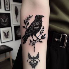 a black bird sitting on top of a branch with leaves and flowers in it's claws