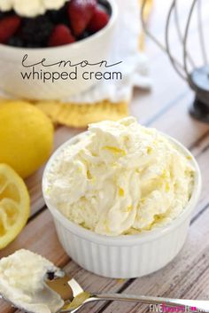 a bowl of whipped cream with lemons and strawberries in the background