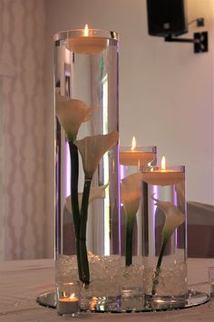 three candles are in the center of a vase with flowers and ice cubes around it