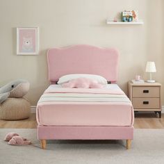 a pink bed sitting in a bedroom next to a window