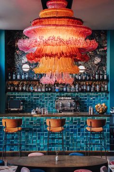 a colorful chandelier hanging over a bar with stools in front of it