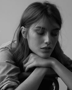 a black and white photo of a young woman with her hands on her chest looking down