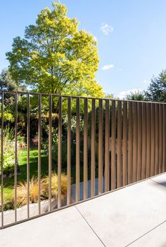 a tall metal fence next to a lush green park