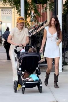 a man and woman walking down the street with a baby in a stroller next to them