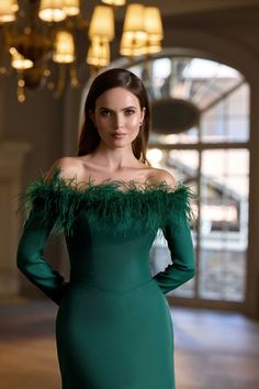 a woman in a green dress posing for the camera with her hands on her hips