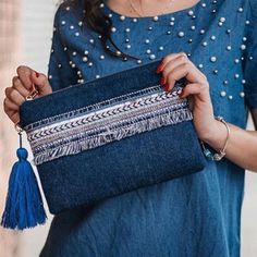 a woman holding a denim purse with tassels