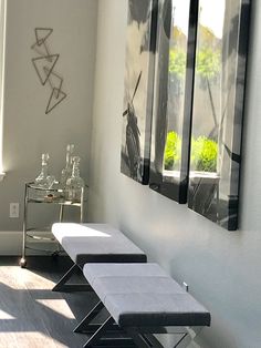 two benches are sitting in the corner of a room with three mirrors on the wall