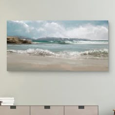 an ocean scene with waves crashing on the shore and mountains in the distance, framed canvas print