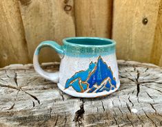 a blue and white mug sitting on top of a tree stump