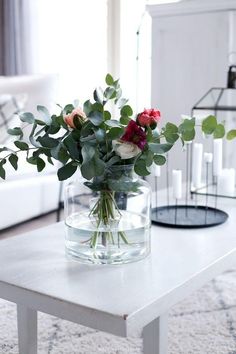 a vase filled with flowers sitting on top of a table next to a white couch