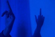 two hands pointing at something in the dark blue light, with one hand raised up